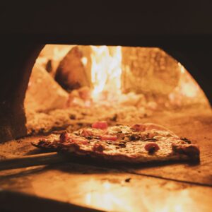 Close up of pizza in a wood-fired oven in a restaurant.